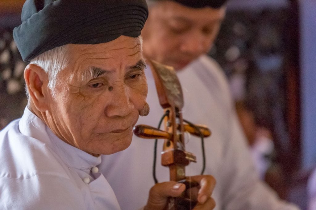 Cao Dai Follower Playing Music - VIETNAM - Must do day trip: Cu Chi tunnels and Cao Dai Temple from Ho Chi Min City